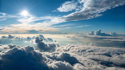 Aerial view of sunlit clouds and blue sky with sun rays shining through above