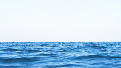 Fototapeta premium Calm blue ocean water with gentle waves under a bright white sky horizon