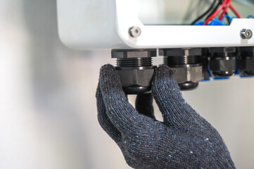 Close up electrician hand with working glove adjusting solar cell inverter 