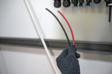 Close up electrician with working glove holding cable wires ready to install in electric mainboard