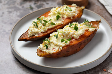 Baked sweet potatoes with creamy cheese topping and fresh herbs. Healthy food