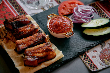 Savory Grilled Meats Served with Fresh Vegetables and Dipping Sauce on a Slate Board, Perfect for a...