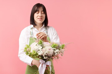 Florist with beautiful bouquet of flowers on pink background, space for text