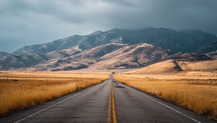 Open road leading into a mountain range under a dramatic sky