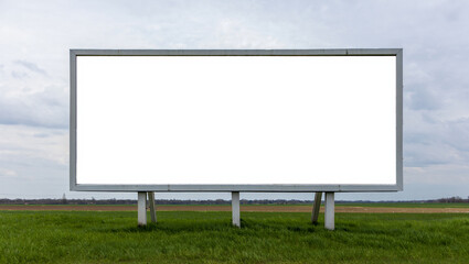 Fototapeta premium Blank billboard in a green field under a cloudy sky