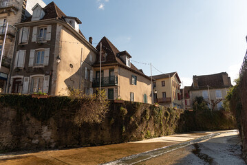 View of the impressive medieval architecture of the small stone houses by a river in the touristic southern French village of Sales de Bearn at sunset.