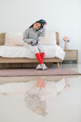 A girl in fencing gear is sitting and rest on the bed