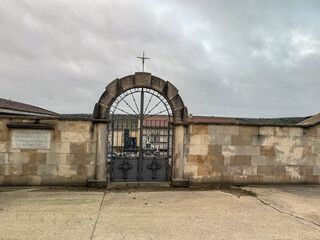 Ornamental iron cemetery gate with stone arch and cross in Dehesa de Montejo