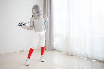 Before the tournament day, a girl dressed in fencing gear are rehearsing in gym