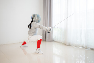 Before the tournament day, a girl dressed in fencing gear are rehearsing in gym