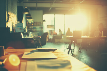 Empty Desk in a Busy Startup Office with Backlit Business People Working