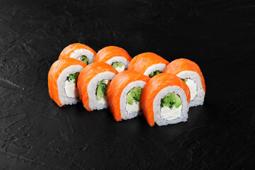 Philadelphia uramaki sushi rolls with salmon, cream cheese, cucumber and avocado on black background
