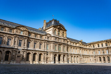 The majestic grandeur of the Louvre Museum's architecture, captured in a vast, empty courtyard