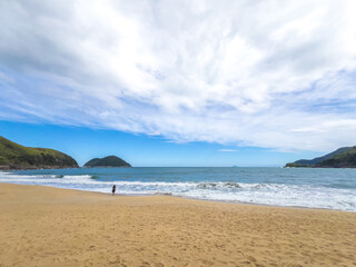 Obraz premium Woman Walking on Remote Tropical Beach with Lush Hills and Ocean View