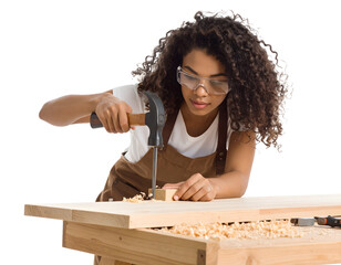 Female woodworker using a hammer, nailing wood pieces together on a woodworking table with shavings