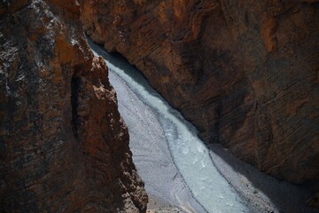 Rocky mountain valley with a narrow stream flowing through.