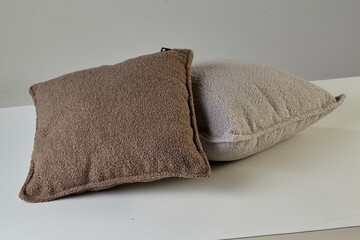Two fluffy square cushions resting on white surface