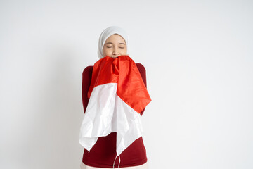 A young woman wearing a hijab embraces a national flag, expressing pride and solidarity. Indonesia...