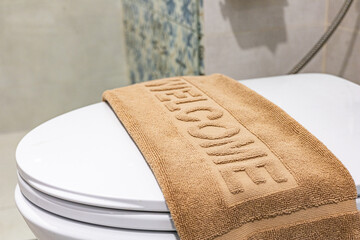 Welcome towel neatly arranged on a toilet seat close up