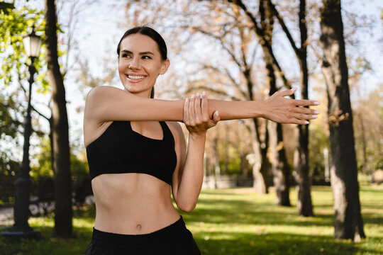 Athletic Caucasian woman stretching outdoors focused on fitness and exercise. A female runner prepares for a run, emphasizing proper warm-up for her daily exercise and running training.