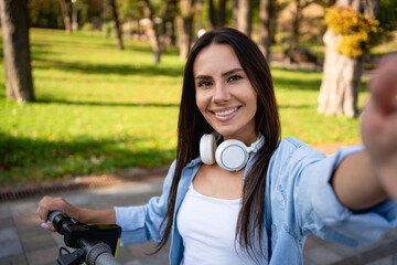 Happy woman take a selfie has video call recording traveling blog while riding on electronic...
