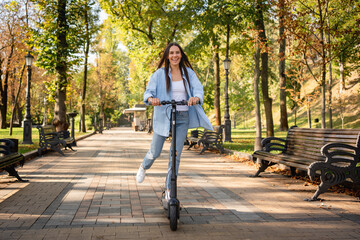 Full body shot of young happy calm fun woman wearing casual clothes riding e-scooter transport...