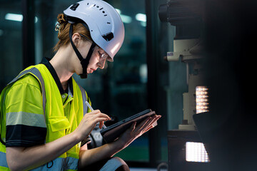 A woman in a yellow vest is using a tablet to take notes
