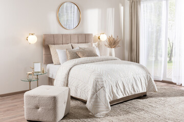 Elegant contemporary bedroom with upholstered beige headboard, gold accent pillows, geometric white...