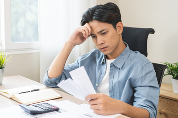 Debt and financial concept, stressed asian young man have a headache while male sitting calculate...