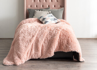 Cozy Bedroom Scene with Peachy-Pink Blanket Draping Over a Bed Base, Soft Gray Cushions, Modern...