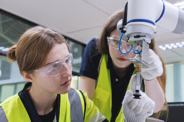 automation machine engineer woman students study and inspection control robot arm machine in robotics engineering academy at university or factory workshop. AI robot technology,