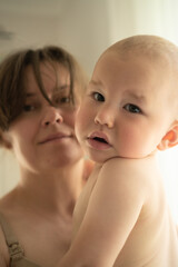 Serene home scene of mother cradling her little one with unconditional love. Beautiful natural moment of maternal affection and quiet connection.