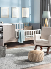 Contemporary baby's room with pastel blue walls, showcasing a gallery mockup of three blank frames,...