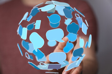 Hand holding a sphere of digital speech bubbles, representing global communication and social media.
