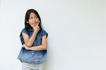 A thoughtful girl look in sleeveless denim top against white background.