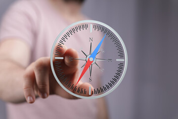A person's finger interacts with a digital compass interface, showing direction and navigation. © vegefox.com