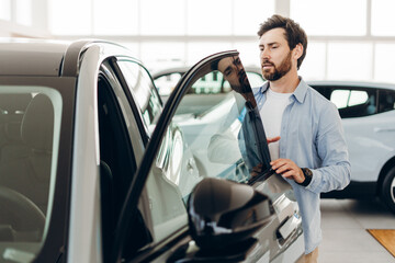 Customer examining new car in dealership showroom