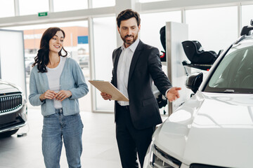 Car salesman showing new vehicle to woman in dealership