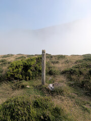 Fogged wooden pole rises above misty mountain landscape - Escape to serene Cantabria, Spain. A...