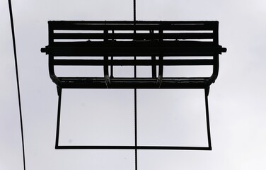 The bottom view of a ski lift, suspended in mid-air, against a pale sky.
