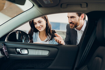 Car salesman showing interior features to potential customer