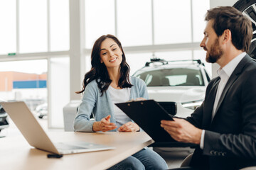 Car salesman showing contract to customer in dealership