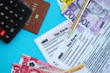 Philippines peso money bills and calculator with tax form on blue. Taxation and accounting concept