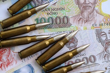 Vietnamese dong currency money bills and rifle bullets. The concept of warfare and gun selling