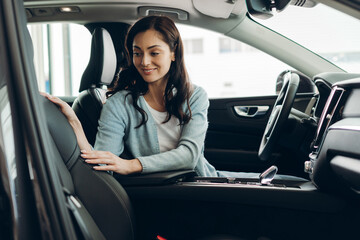 Customer choosing new car in dealership showroom touching leather seat