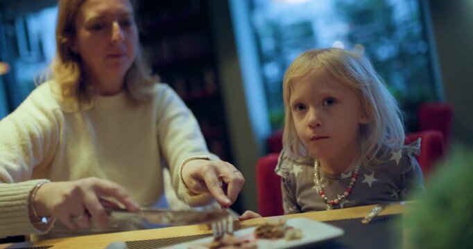 Mother and Daughter Share a Meal: A heartwarming moment as a mom helps her daughter with a napkin at a restaurant.