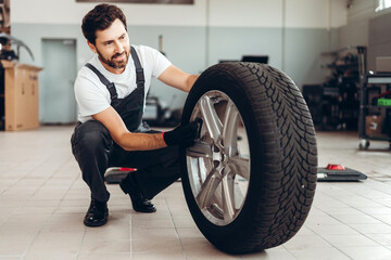 Mechanic inspecting car tire in auto repair shop