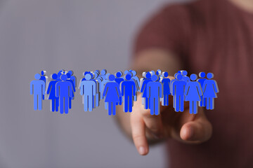 Stock photo of a hand interacting with a 3D digital representation of a diverse group of people.