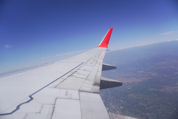 Airplane wing above the clouds during flight, view from airplane window.