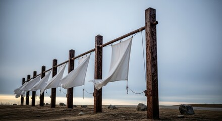 Windswept White Flags on Rusted Posts in a Desolate Coastal Landscape